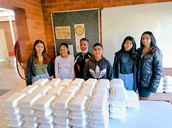 A group of children behind a table with takeaway containers on it