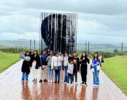 A group of children in front of a structure of Nelson Mandela