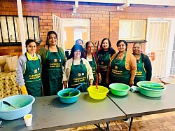 A group of ladies wearing aprons standing behind a table serving meals