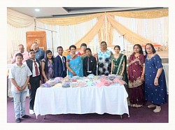 Group of adults and children behind a table displaying knitted items