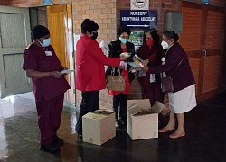 Women handing over knitted items to nurses