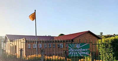 A brick building with green signboard and orange flag