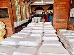 A small group of children behind boxes of packed food