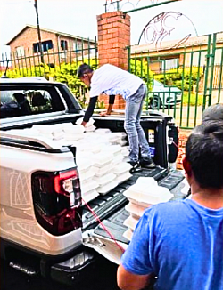 2 boys packing boxed food into a parked van