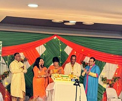 Group of people in traditional Indian attire standing in front of a huge cake